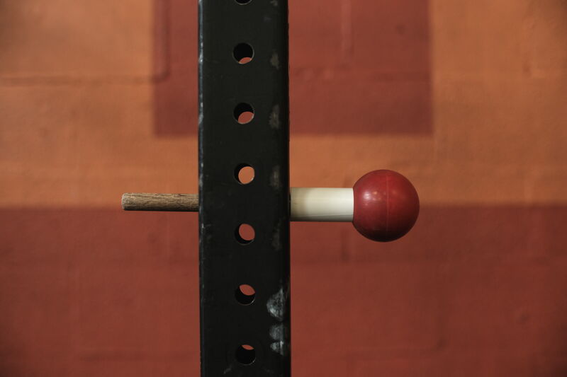 Ball on a Stick — lacrosse ball mounted on a stick in a squat rack